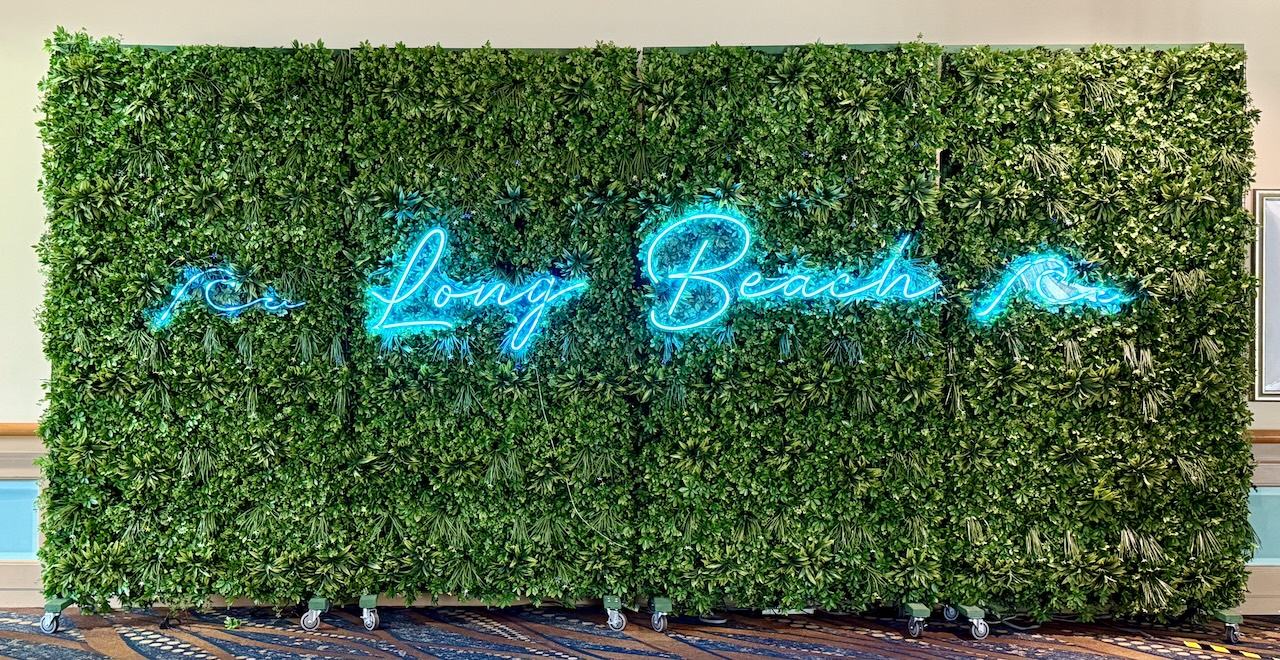 neon sign with waves and “Long Beach” on fake grass walls